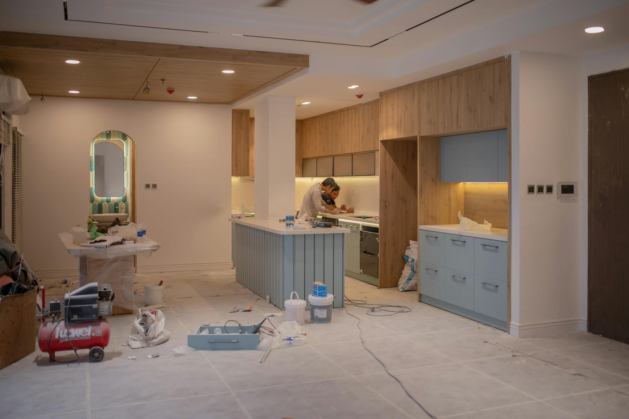 Kitchen undergoing professional cabinet refinishing with protective containment setup