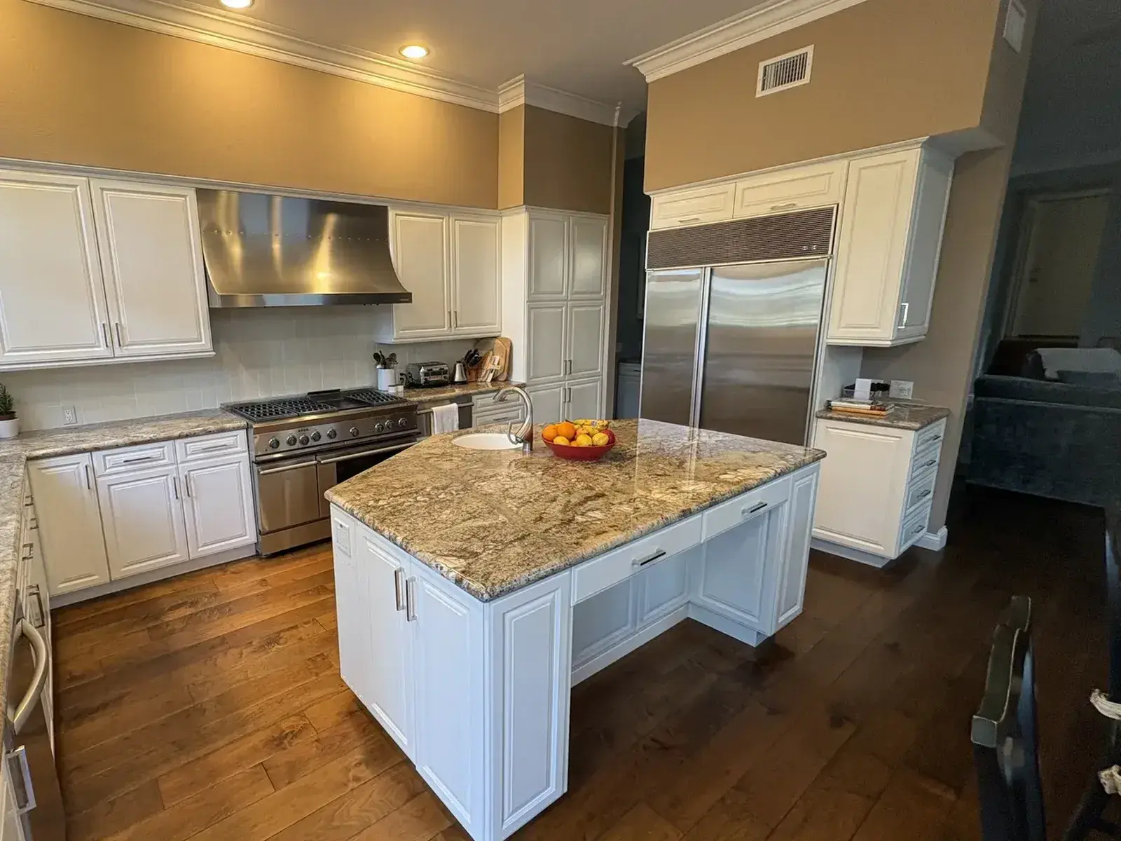 After: Same range and fridge wall: brighter cabinets, cleaner lines, one kitchen transformed.