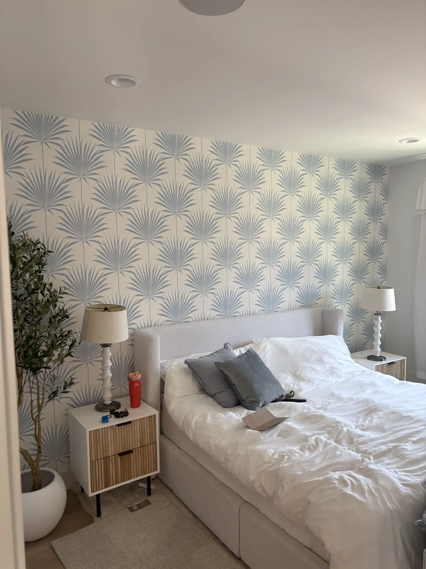 Palm leaf wallpaper installed behind a bedroom headboard