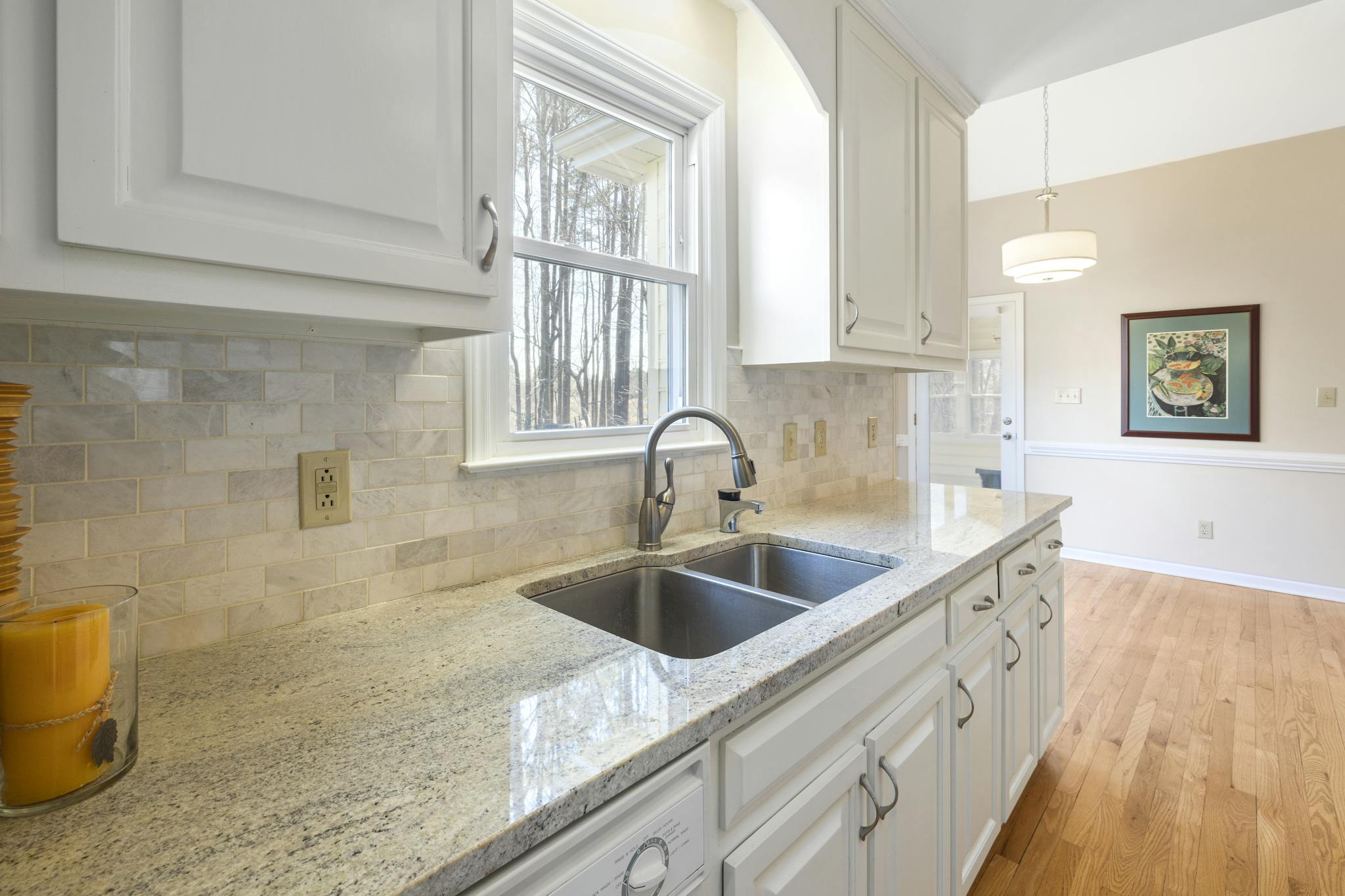 Spacious white kitchen interior with granite countertops and natural light.